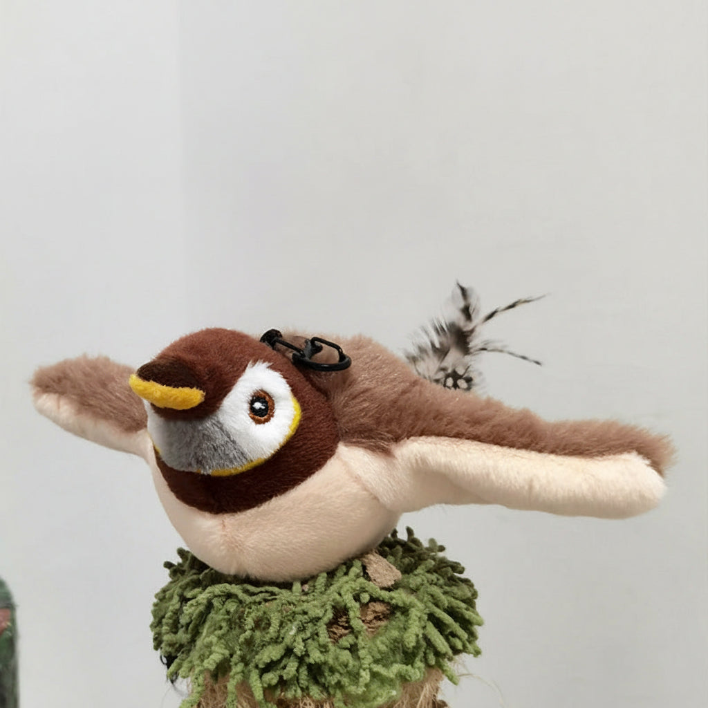 Plush bird toy with moving wings on a grassy base.