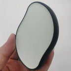 Hand holding a black and gray Crystal Hair Eraser against a white background