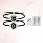 Two black and silver bracelets with celestial designs on a light pink background.